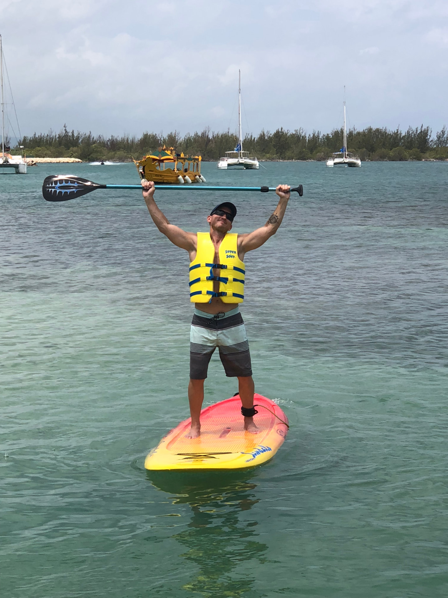 Kevin paddleboarding with his paddle raised overhead