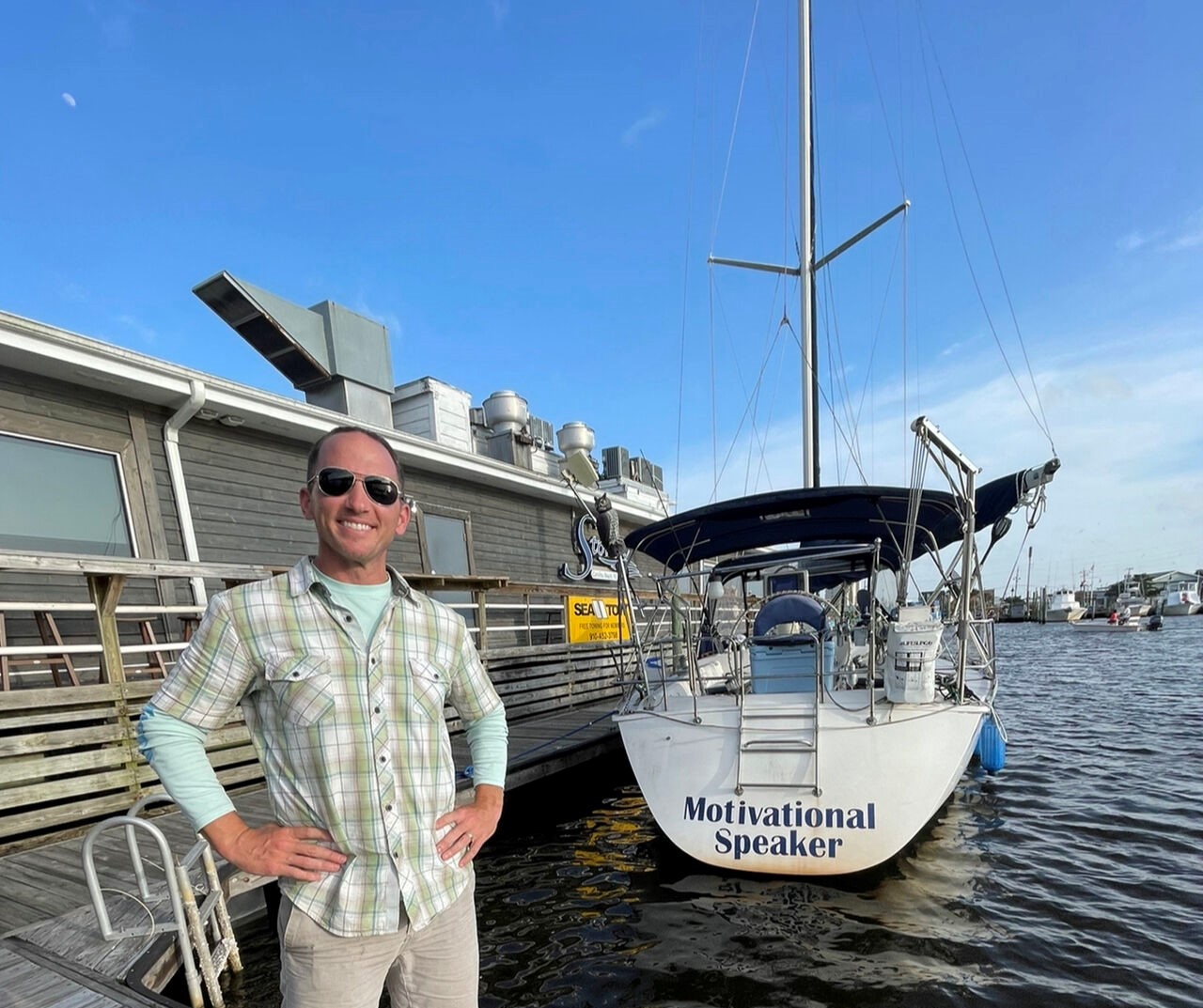 Kevin beside a sailboat named Motivational Speaker