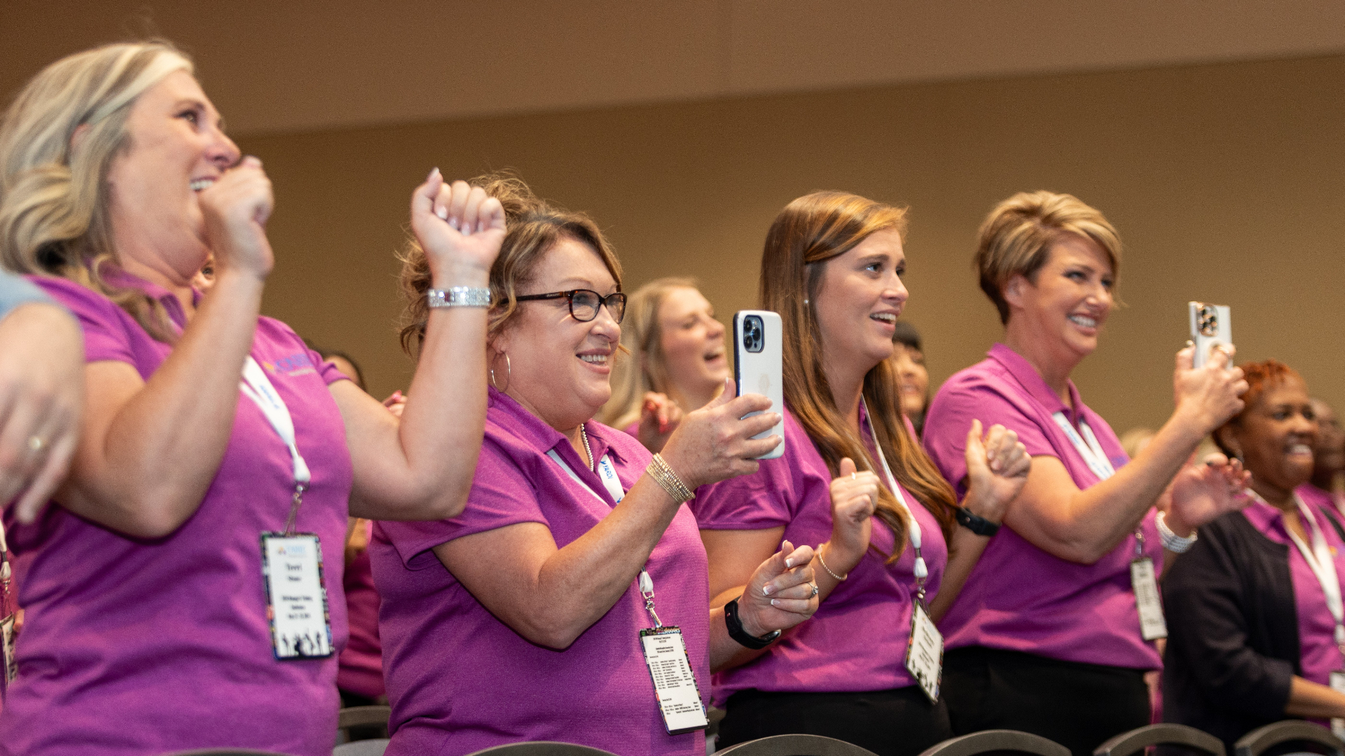 Audience of managers on their feet cheering at a conference
