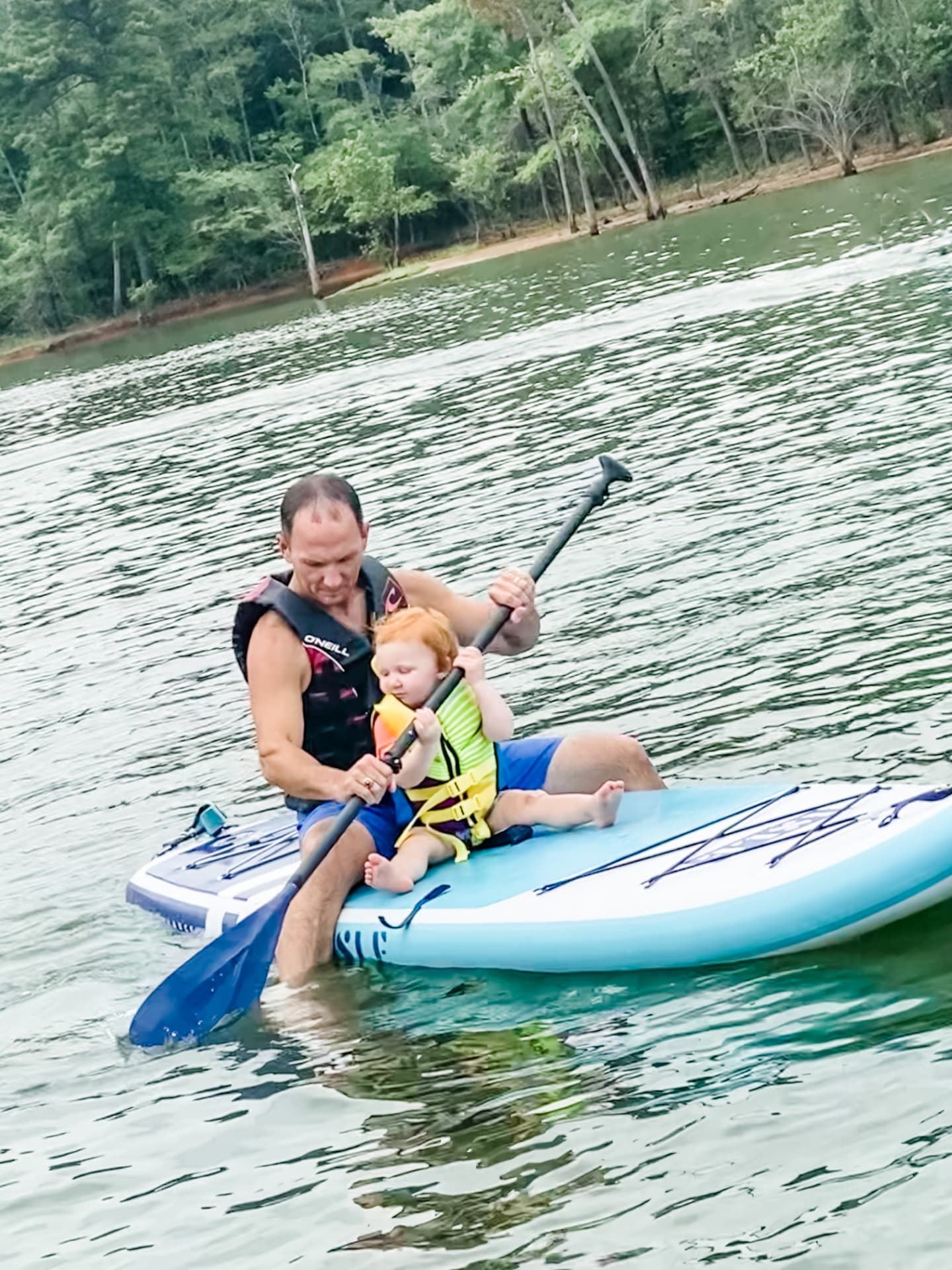 Kevin paddleboarding with his daughter on a lake